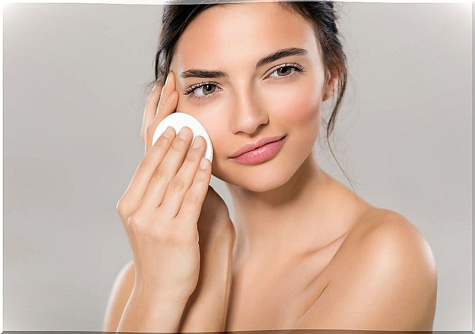 Woman wiping her face with a cotton pad.