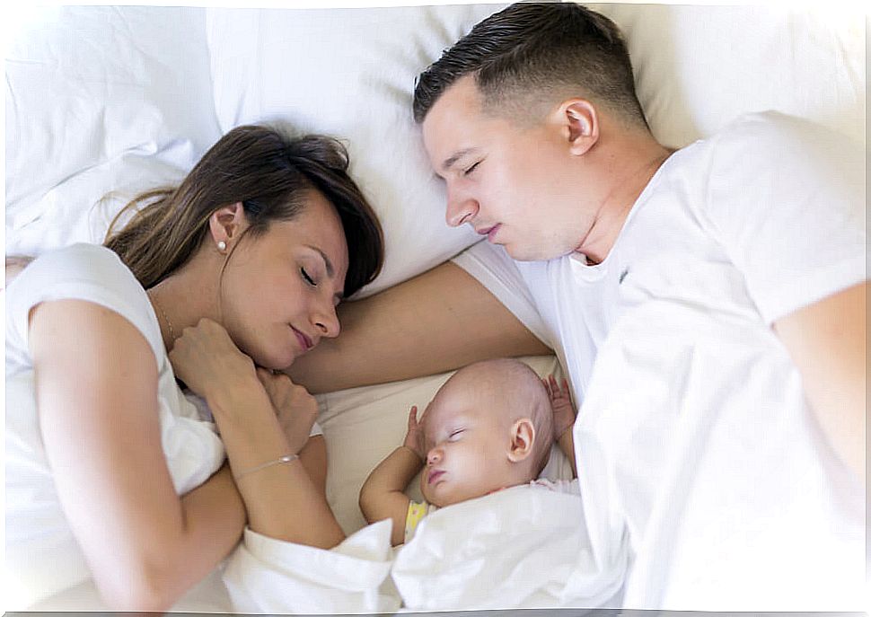 Parents sleeping with their baby.